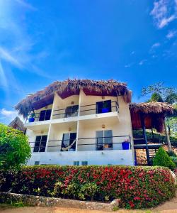 a large white building with a thatch roof at Tayrona Angel Lodge in El Zaino