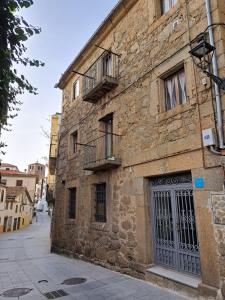 - un vieux bâtiment en pierre avec 2 balcons et une porte dans l'établissement Bosque de los sauces, à Béjar
