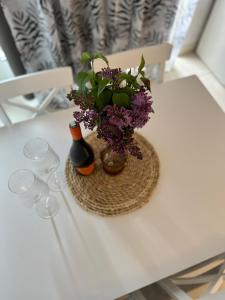 a white table with a vase with purple flowers on it at Etno village Mihailovic in Herceg-Novi