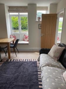 uma sala de estar com um sofá, uma mesa e janelas em Scotland Lodge Farm, Stonehenge em Salisbury