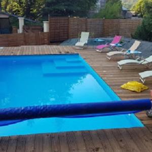 una piscina blu su una terrazza in legno con sedie di chambre zen a Condé-sur-Noireau