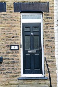 a black door on the side of a brick building at Delightful 2 bed town centre house, sleeps 4 in Barnsley