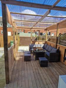 a patio with a couch and a table on a wooden deck at Pav's Den in Ince-in-Makerfield