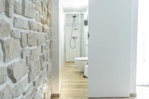 bagno con parete in pietra e servizi igienici. di L&B amphitheater apartments a Pola (Pula)