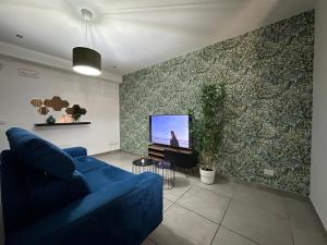 sala de estar con sofá azul y TV en Amour Içi appartamenti e suite in centro en Mascalucia