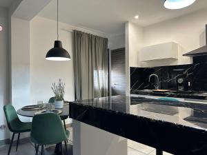 una cocina con encimera negra y sillas verdes en Amour Içi appartamenti e suite in centro en Mascalucia