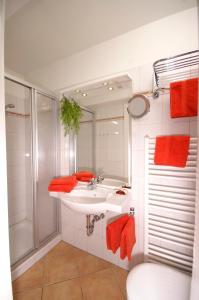 ein Bad mit einem Waschbecken, einer Dusche und roten Handtüchern in der Unterkunft Pension Hermer in Grömitz