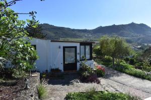 Una pequeña casa blanca con una montaña al fondo. en Casita de la Montaña de María, en Tegueste