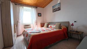 una camera da letto con un letto con una coperta rossa e una finestra di Appartamento Luca e Giulia a San Bernardino