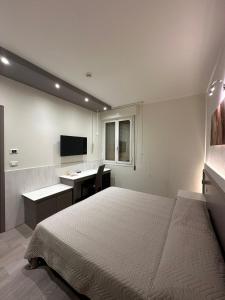 Schlafzimmer mit einem Bett, einem Schreibtisch und einem TV in der Unterkunft Hotel Europa in Cento