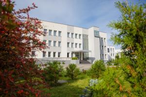 a white building with trees in front of it at Hotel Quattro in Szczecinek