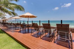 a deck with chairs and tables and umbrellas on the beach at Flat Pietra in Florianópolis