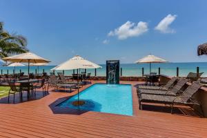 a deck with a swimming pool with chairs and umbrellas at Flat Pietra in Florianópolis