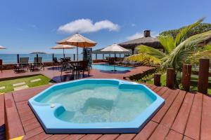 a hot tub on a deck next to the ocean at Flat Pietra in Florianópolis