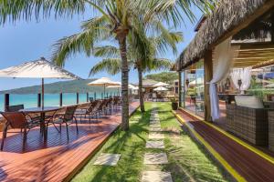 an outdoor patio with tables and chairs and the ocean at Flat Pietra in Florianópolis