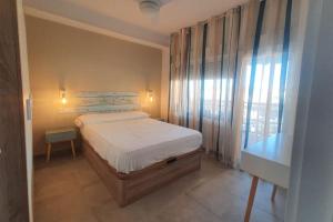 a small bedroom with a bed and a window at SweetWater Beach - Apartamento turístico en zona puerto in Aguadulce