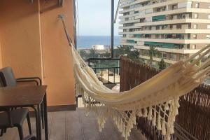 a hammock on a balcony with a view of the ocean at SweetWater Beach - Apartamento turístico en zona puerto in Aguadulce