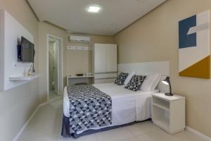 a bedroom with a bed and a tv in it at Flat Pietra in Florianópolis
