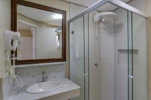 a bathroom with a sink and a shower with a mirror at Flat Pietra in Florianópolis
