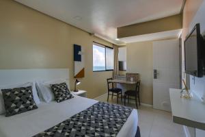 a bedroom with a bed and a table and a tv at Flat Pietra in Florianópolis