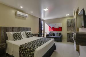 a bedroom with a bed and a living room at Flat Pietra in Florianópolis