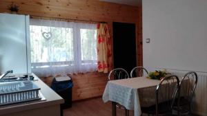 eine Küche mit einem Tisch mit Stühlen und einem Fenster in der Unterkunft Oleandria-,, Domek Poziomeczka" nr 33 -ogrzewany w okresie jesienno-zimowym in Biskupiec