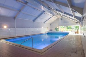 a large indoor swimming pool with blue water at Luxe chalet Beek (gem Montferland) bosrijk, rust en privacy in Beek