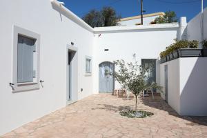 a courtyard of a white house with a tree in the middle at Serendipity Living in Kythira