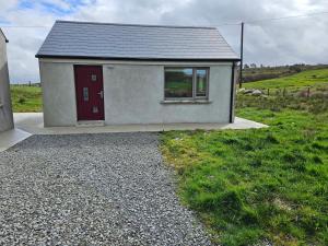 a small house with a red door in a field at Suaimhneas in Lahinch