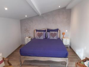 a bedroom with a bed with purple sheets and pillows at Un petit coin de paradis à Haute Jarrie in Jarrie