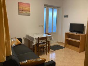 sala de estar con sofá, mesa y TV en Apartments Deranja, en Dubrovnik