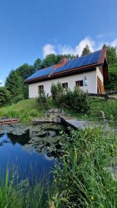 ein Haus mit Sonnenkollektoren neben einem Teich in der Unterkunft Jaworowy Stok z widokiem na góry i ogrodem in Jugów