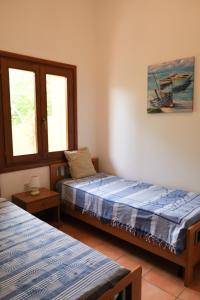 two beds in a room with two windows at Casa Adriana - Costa Paradiso in Costa Paradiso