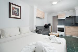 a bedroom with a white bed and a kitchen at Panos Marina Apartment P1 in Porto Rafti