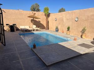 a swimming pool with an umbrella and a patio at Villa C à 5km du centre in Marrakesh