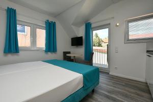 a bedroom with a bed with blue curtains and a balcony at City-Hotel Zuffenhausen in Stuttgart