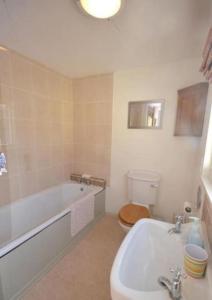 a bathroom with a tub and a toilet and a sink at Lime Cottage in Minehead