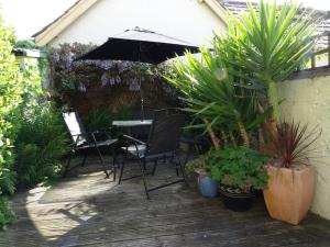 a patio with a table with an umbrella and plants at Lime Cottage in Minehead