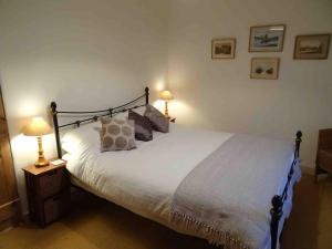 a bedroom with a large white bed with two lamps at Lime Cottage in Minehead