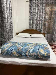a bed with a blue and gold blanket on it at Orange Bari Farmstay in Darjeeling