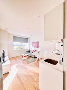een keuken en een woonkamer met witte muren en houten vloeren bij LUXX Apartment & Suites, London Heathrow Airport, Terminal 4, Piccadilly underground Train station nearby! in New Bedfont