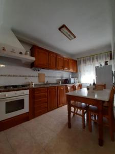 una cucina con armadi in legno, tavolo e frigorifero di Lugar do Sonho Apartamento a Cercal