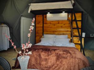 a bed in a tent with a flower vase on a table at Vardzia Glamping in Vardzia