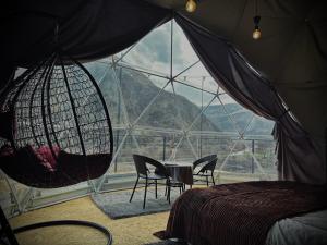 ein Schlafzimmer mit einem großen Fenster mit Stühlen und einem Tisch in der Unterkunft Vardzia Glamping in Wardsia