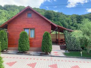 a red house with trees in front of it at Pensiunea Azurul in Sovata