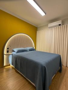 1 dormitorio con cama y pared amarilla en Luxo colado no Shopping en Franca