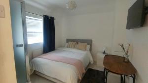1 dormitorio con cama, mesa y ventana en Modern Bromely House in BR5 en Foots Cray