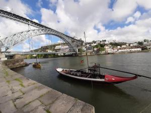 un barco en el agua bajo un puente en Muralha da Barca Apartamentos RNAL nº13939 Al,5848 Al, 6419 AL-Chamada para a rede móvel nacional, en Oporto