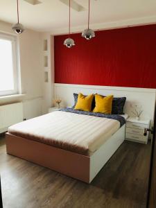 een slaapkamer met een rode muur en een bed met gele kussens bij Apartamentai Kęstučio g. Šilutėje in Šilutė