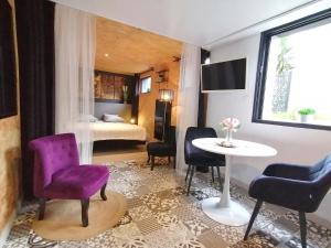 un salon avec une chaise violette et une table dans l'établissement le Ti'Cocoon, à Langueux